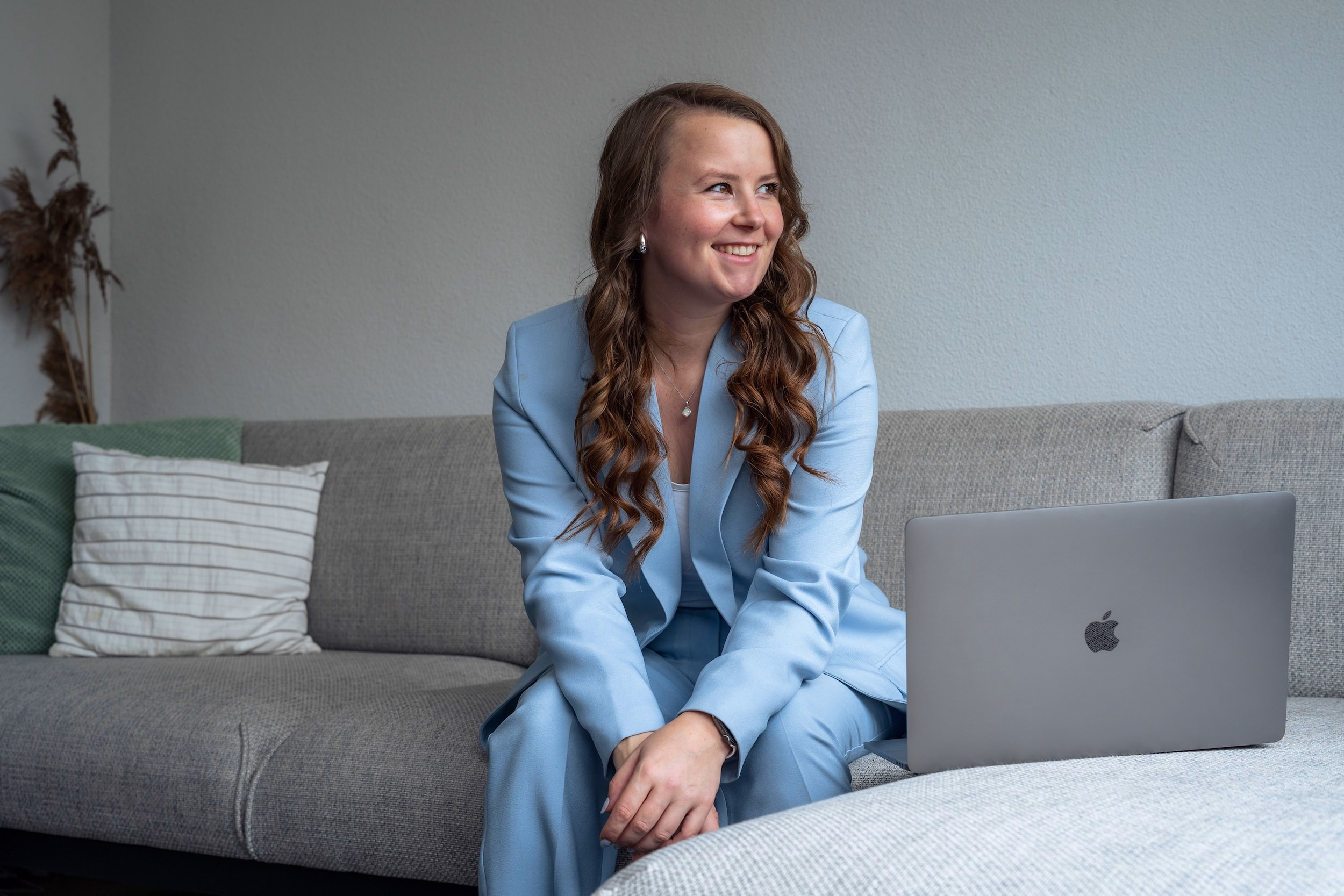 Bedrijfsfotografie Alphen aan den Rijn - Model met laptop en lachend naar buiten op bank