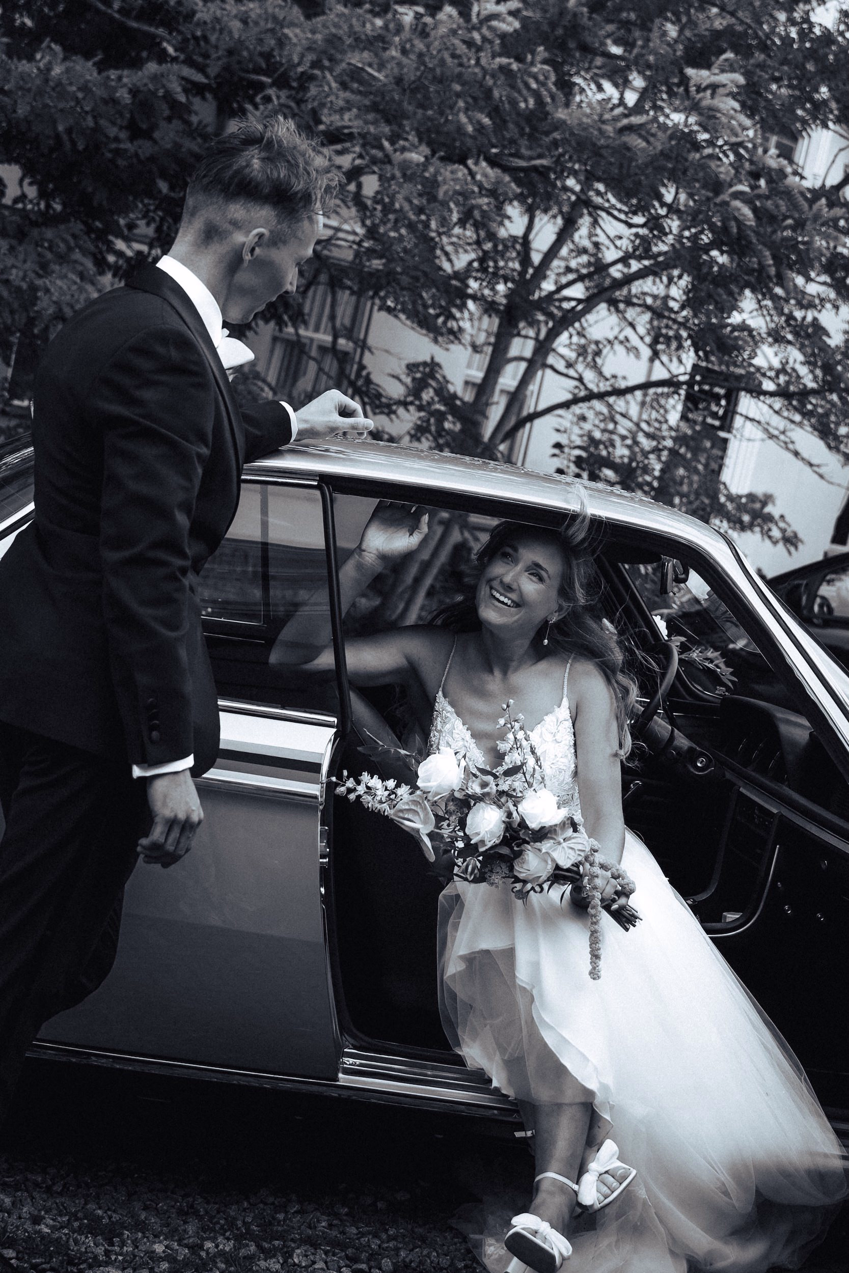 Trouwfotografie Zuid-Holland - Bruidspaar poserend in de auto zwart wit foto