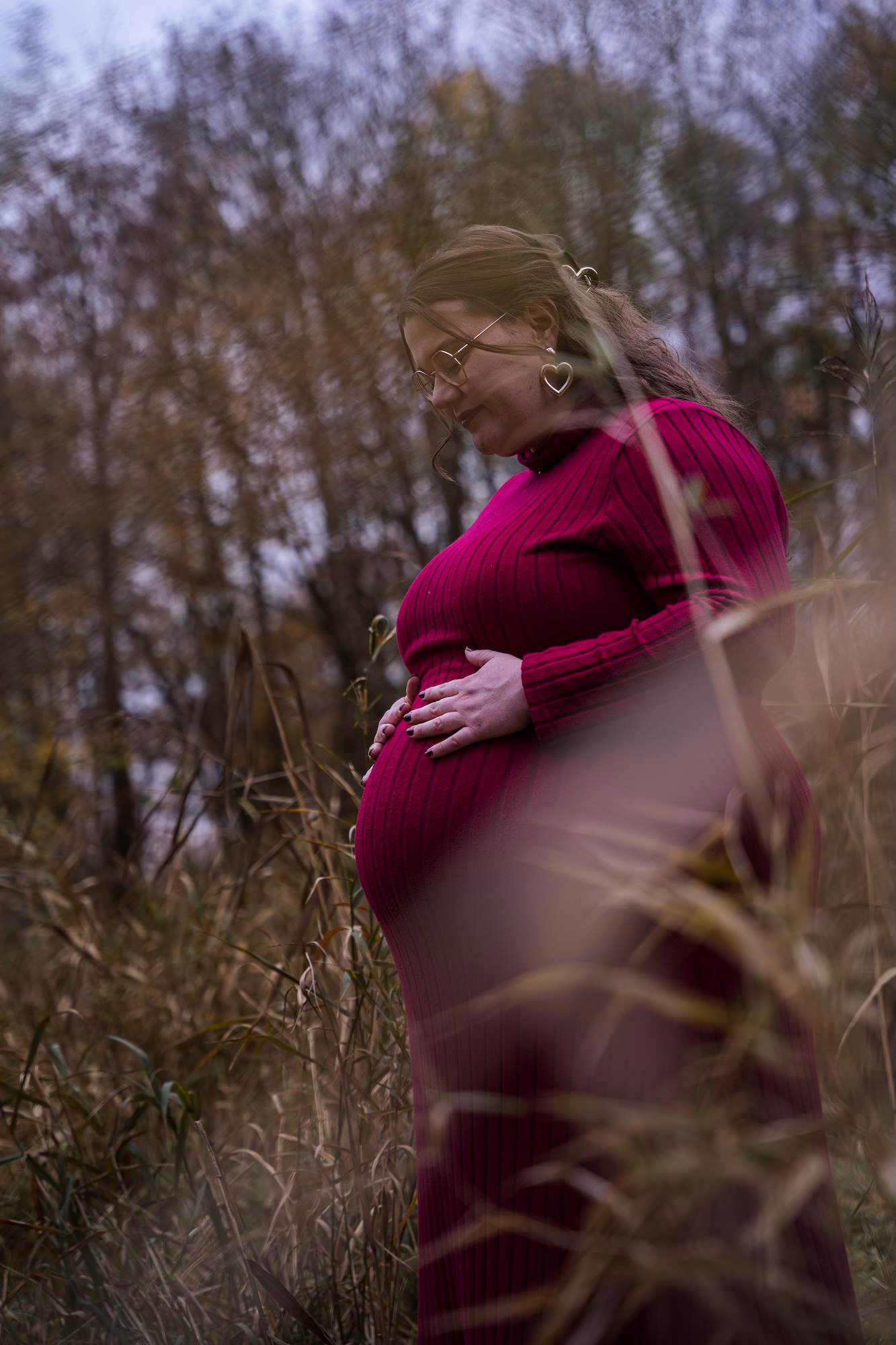 Zwangerschapsfotoshoot in Alphen aan den Rijn — zwangere vrouw tussen riet met roze jurk