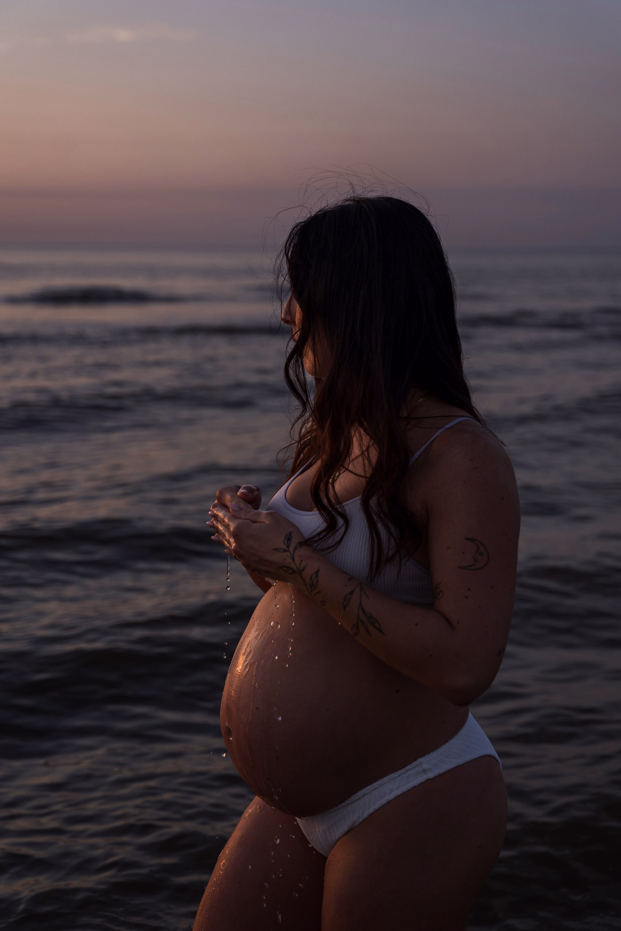 Zwangerschapsfotoshoot in Noordwijk — zwangere vrouw in bikini in de zee met water